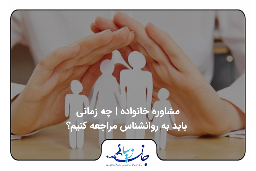 کسی پشت میزی نشسته و دو دست خود را مانند یک خانه بالای یک خانواده که با کاغذ سفیددرست شده اند قرار داده است
